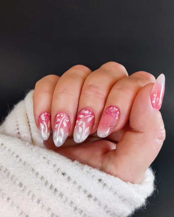 Medium almond nails fading from pink to clear, with hand-painted white winter branches and fine glitter.