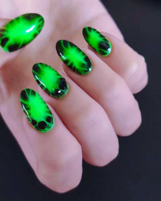 Close view of the same neon green and black set, showing the burst on each nail and the black stones.