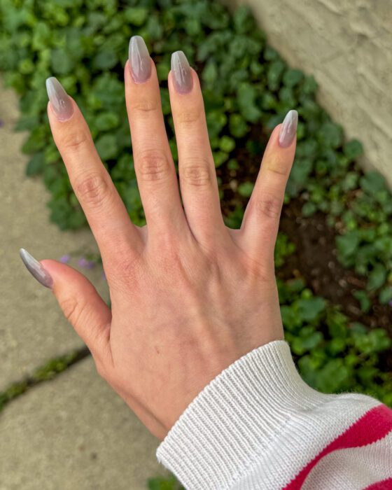 Long coffin extensions in translucent smoke grey, photographed outdoors against green foliage.