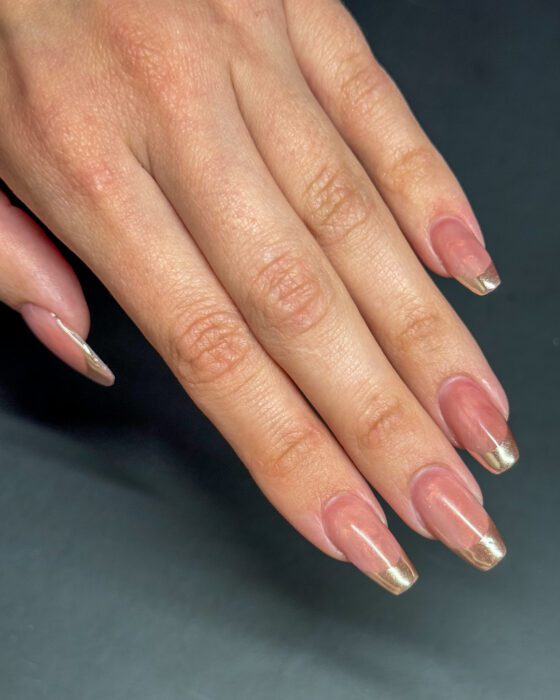 The hand turned to the side, where the gold tips read almost as metal at the free edge.