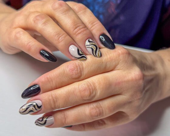 Closer view of the accent nails, showing the repeated black waves and the fine gold glitter line running alongside.