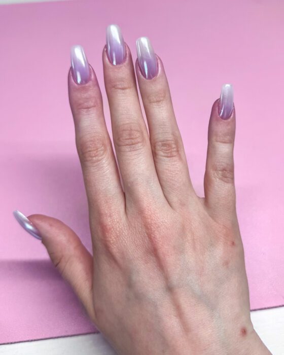 The same hand from above, the pearl chrome reading almost white at the tips.