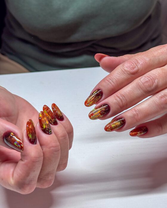 Angled view showing the brighter orange-gold sections and multicoloured foil flashes across the amber design.