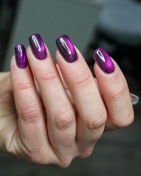 The purple hand with bright reflective bands running at an angle across the nails.