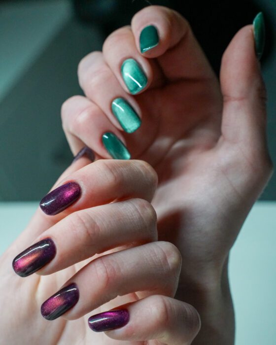 Hands crossed, the green and purple cat-eye sets visible together.