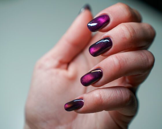 Close view of the purple hand, bright magenta reflective bands across the nails.