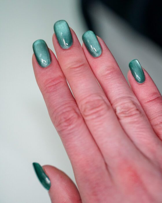 The green hand with a pale teal-silver band running across the nails.