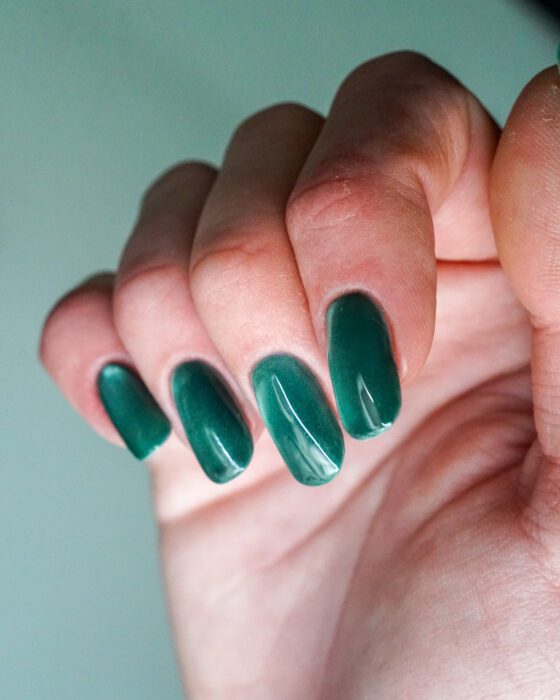 The green hand curled, darker emerald edges framing the cat-eye flare.