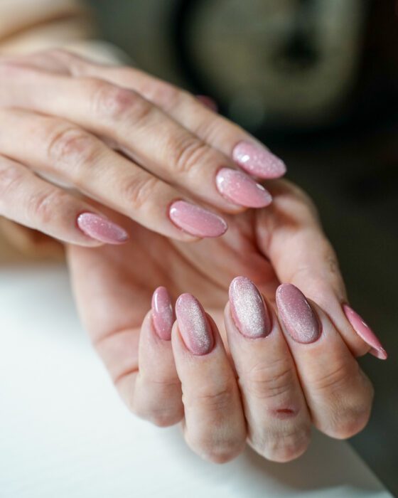Hands crossed, pearly pink reflective bands visible on several nails.