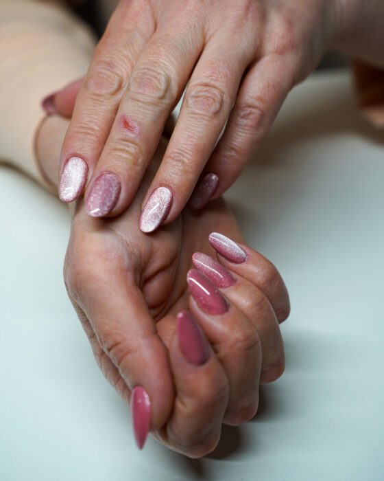 Hands crossed from another angle, brighter silver-pink cat-eye reflection on the upper hand.