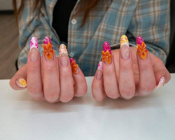 The same set held upright, showing the raised flowers and the gold beads at the cuticle line.