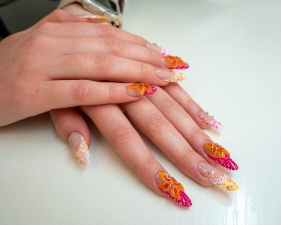 Hands resting crossed, showing the sheer nude base under the painted tips and the full almond length.