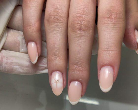 Close view of the same white French set, showing the soft-edged flower on the accent nail.