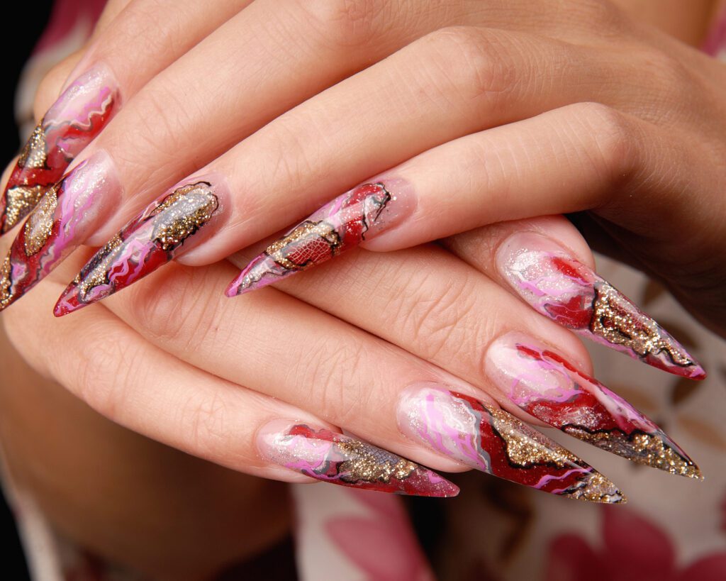 Long stiletto nails with red and gold marbled geode art and glitter veins
