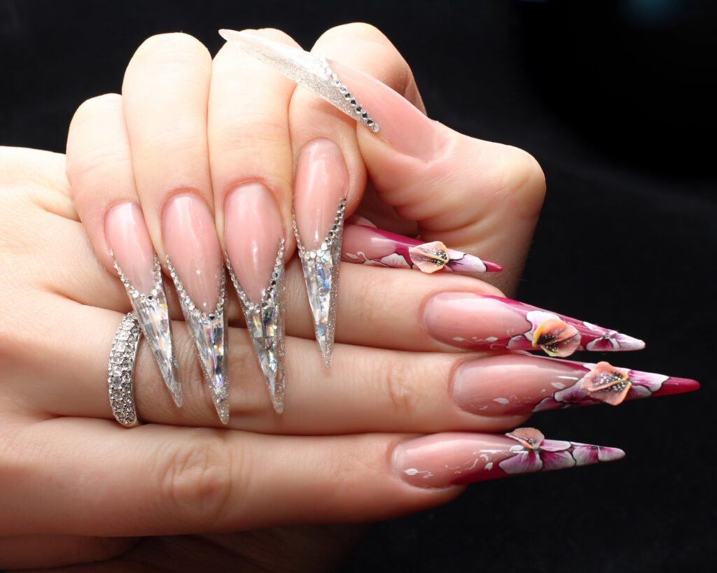 Long stiletto nails with painted pink lilies and clear crystal-encrusted tips