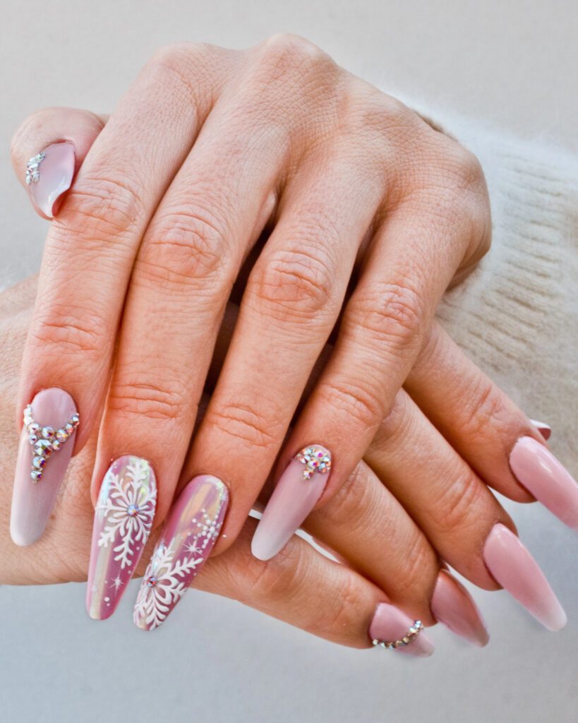 Long coffin nails in pale pink with three-dimensional snowflake art and clustered crystals