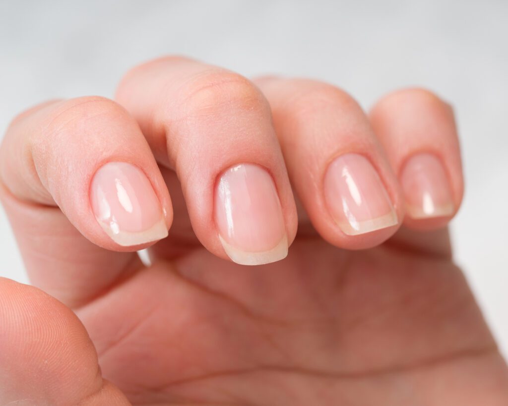 Close view of short natural nails with a pale free edge and a soft pink nail bed