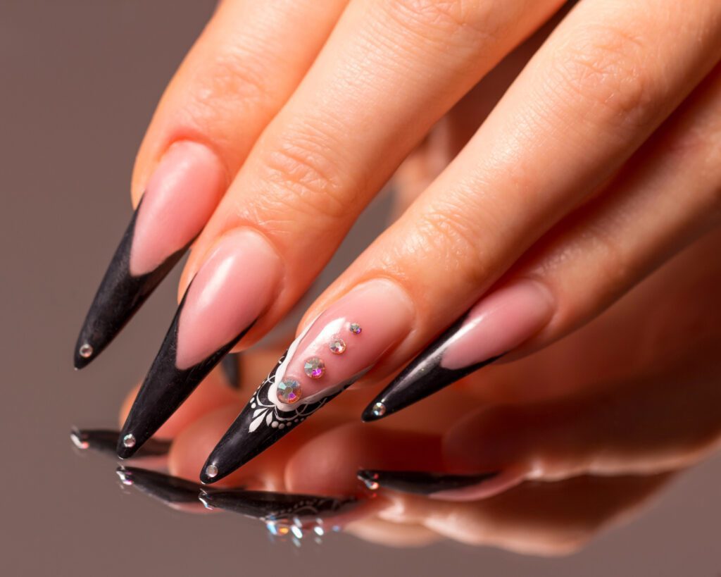 Long stiletto nails with black tips, white lace detail and scattered crystals