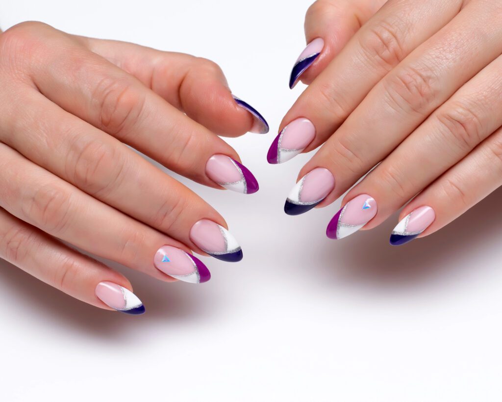 Two hands with almond nails in white, purple and navy French tips of varying shapes