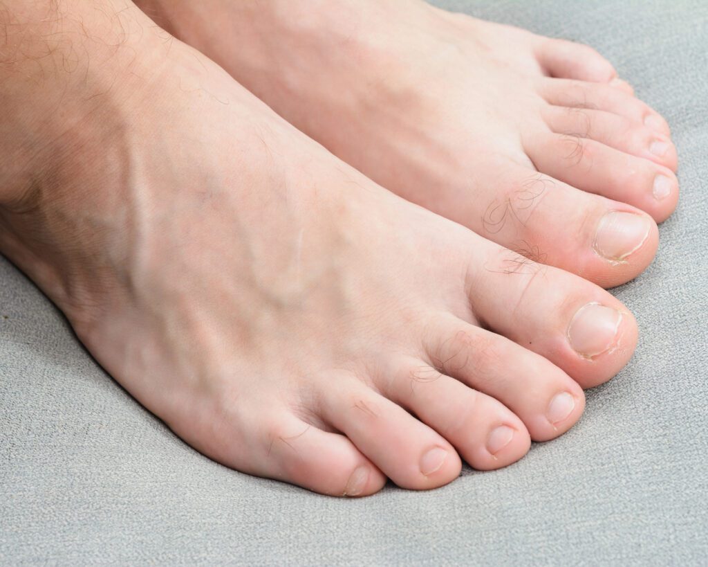 Bare male foot with short natural toenails resting on grey fabric