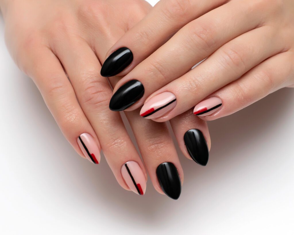 Almond nails alternating glossy black and nude with fine red and black stripe accents
