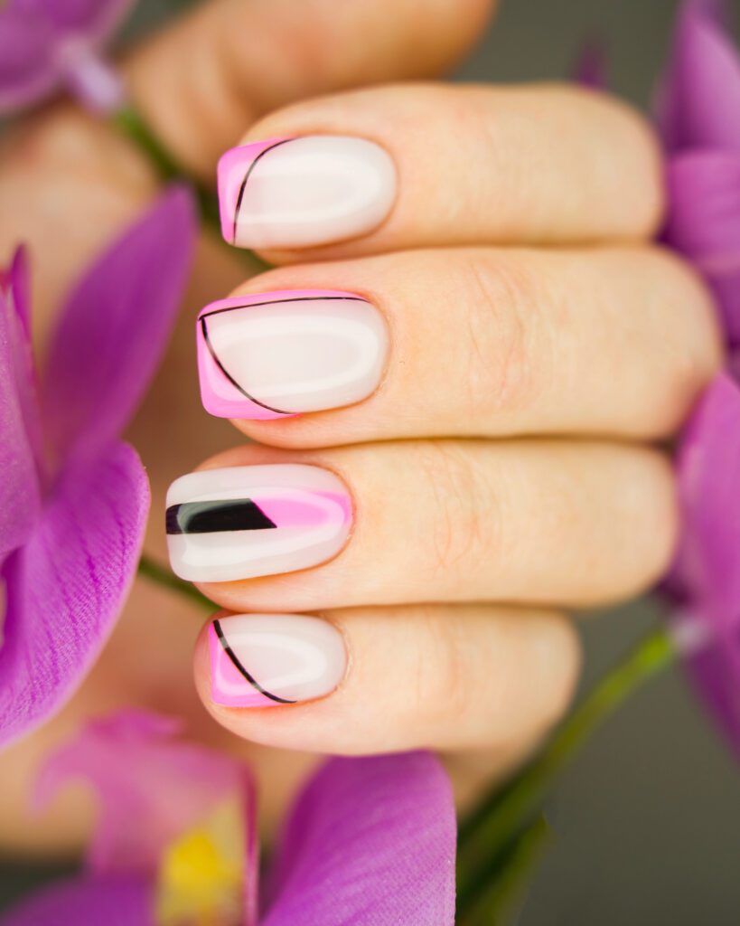 Squared nails in milky white with neon pink French tips and fine black liner, against purple orchids