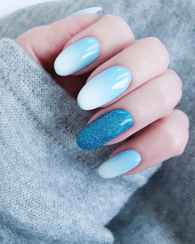 Almond nails in pale blue and white ombre with one turquoise glitter accent nail