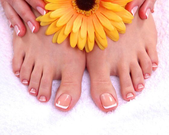 Close-up of toenails with a sheer nude base and crisp white French tips